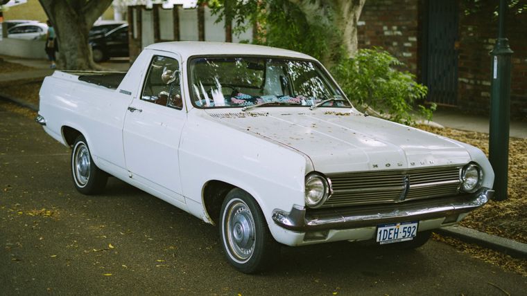 A white Holden ute parked at the kerb of a leafy suburban street, photographed from the front three-quarter angle.