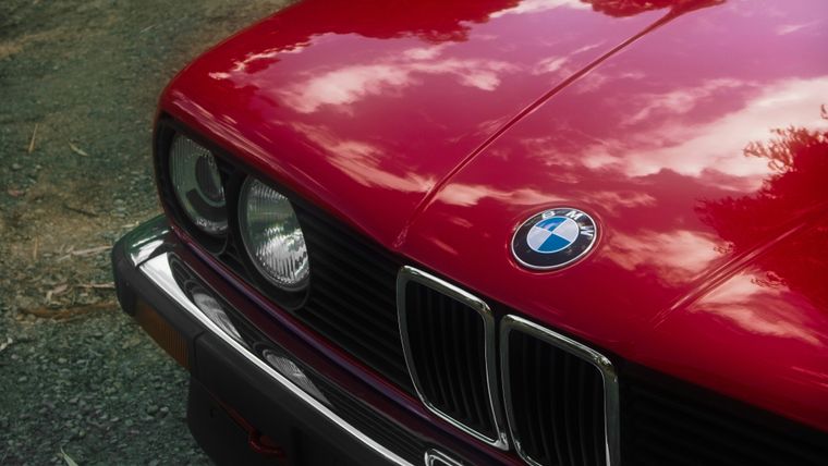 Close-up of a red classic BMW sedan's front end and Victorian number plate